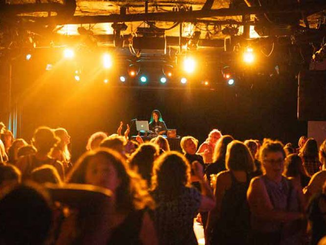 Crowd dancing under stage lights with a DJ
